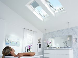 woman in bathtub looking up skylights that have the blinds slightly down in sydney